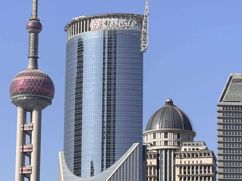 Shanghai skyline with the Oriental Pearl Tower and several modern high-rise buildings under a clear blue sky.