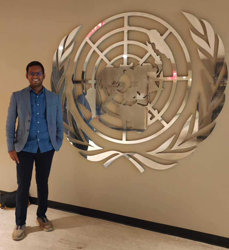 The article’s author, Vineel Reddy Pindi, posing beside the United Nations emblem.